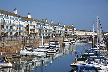 England, East Sussex, Brighton, view over boats moored in the Marina with apartment buildings behind.