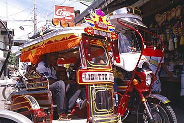 PHILIPPINES Marinduque Island Boac Moriones Festival. Close up of brightly coloured tricycle with pasengers in side cart