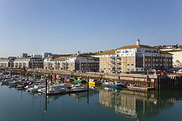 England, East Sussex, Brighton, view over boats moored in the Marina with apartment buildings behind.