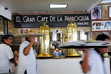 Mexico, Veracruz, Cafe El Gran Cafe de la Parroquia interior with waiters carrying laden trays past bar area.