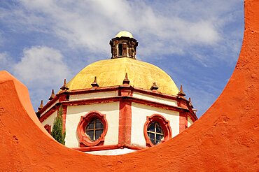 Mexico, Bajio, San Miguel de Allende, Dome of the Parroquia church part framed by orange painted wall.