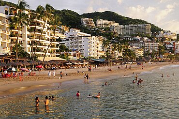 Mexico, Jalisco, Puerto Vallarta, View of Playa Los Muertos beach overlooked by hotels and apartments and lined with bars cafes and beach shades. People on beach and in the water.