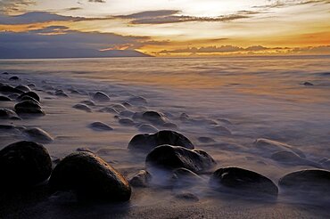 Mexico, Jalisco, Puerto Vallarta, Waves and rocks on beach at sunset.