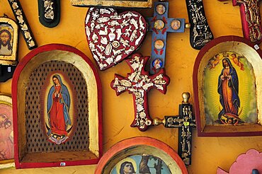 Mexico, Michoacan, Patzcuaro, Religious kitsch art displayed on yellow painted wall.