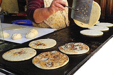 Mexico, Bajio, San Miguel de Allende, Cropped shot of woman making tortillas turning them as they cook on griddle.1