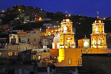 Mexico, Bajio, Guanajuato, Church of San Francisco at night with barrios on hillside beyond.