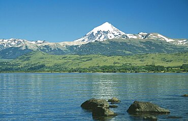 ARGENTINA Neuquen Lanin National Park View over bolders of Huechulafquen Lake toward snow capped Lanin Volcano.