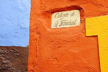 Mexico, Bajio, Guanajuato, Street sign and brightly painted exterior walls of buildings.