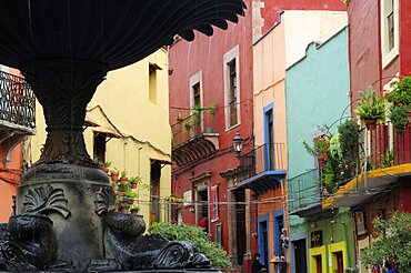 Mexico, Bajio, Guanajuato, Partly seen fountain in foreground of colourful buildings in the Plaza del Baratillo.