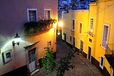 Mexico, Bajio, Guanajuato, Elevated view over street corner at night with painted building facades balconies and illuminated street lights.