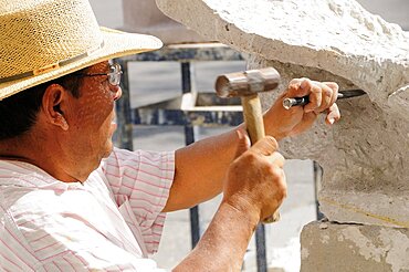 Mexico, Jalisco,  Guadalajara, Plaza de la Liberacion Sculptor working stone with hammer and chisel