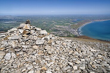 Ireland, County Down, Mourne Mountains, A cairn on the summit of Slieve Donard with Newcastle and its beach in the background