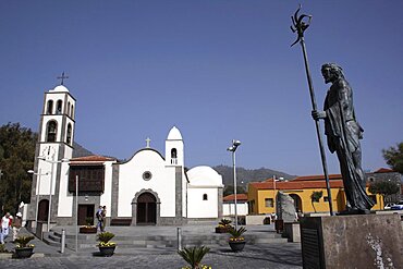 Spain, Canary Islands, Tenerife, Santiago del Teide Exterior of church with statue of Guanche chief in the foreground.