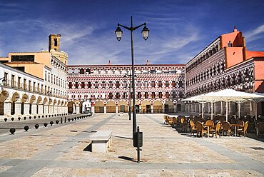 Spain, Extremadura, Badajoz, Colourfully painted buidlings in the Plaza Alta with Espantaperros tower behind.