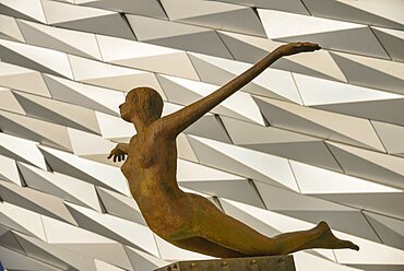 Ireland, North, Belfast, Titanic Quarter, Titanic Belfast Visitor Experience, 'Titanica' sculpture by Rowan Gillespie with section of the building in the background.