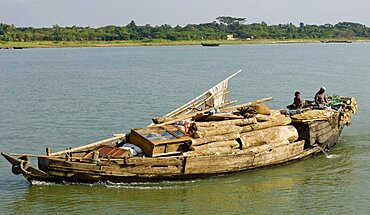 Bangladesh, Industry, Transport, Boat heavily laden with cargo of timber and furniture on river.