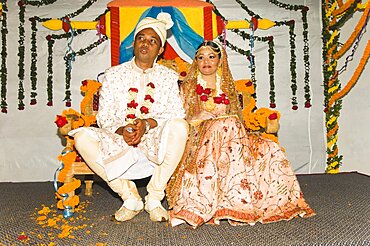 Bangladesh, Dahka, Bride and groom dressed up in glitzy jewellery and flowers for their wedding.