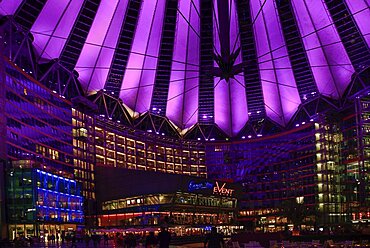 Germany, Berlin, Potzdamer Platz, Sony Centre with glass canopied roof over central plaza at night.