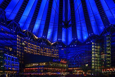 Germany, Berlin, Potzdamer Platz, Sony Centre with glass canopied roof over central plaza at night.