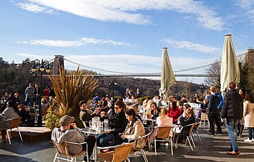 England, Bristol, Drinkers on the terrace of the White Lion Bar with a view of the Clifton Suspension Bridge.