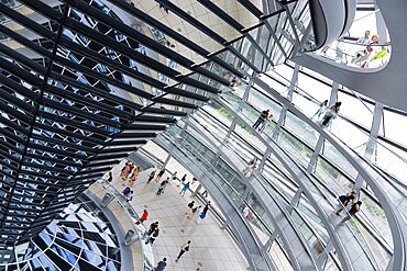 Germany, Berlin, Mitte, Tiergarten, interior of the glass dome on the top of the Reichstag building designed by architect Norman Foster with a double-helix spiral ramp around the mirrored cone that reflect light into the debating chamber of the Bundestag below.