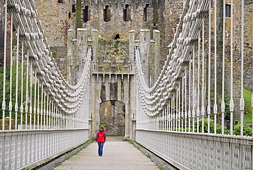 Wales, Conwy, Conwy Suspension Bridge with figure walking towards the walls of Conwy Castle.