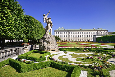 Austria, Salzburg, Mirabell Palace and Gardens with statue and flowerbeds in the foreground.