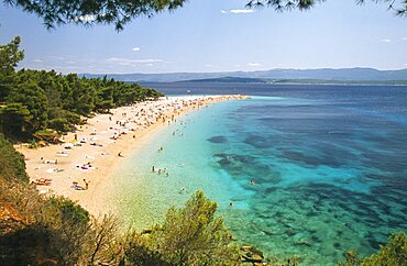 CROATIA Brac Island Bol View over Zlatni Rat Beach lined with trees and scattered bathers