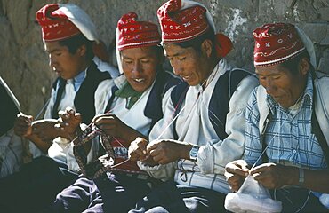 PERU Puno Lake Titicaca Taquile Island.  Line of men knitting.