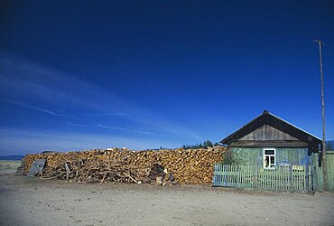 RUSSIA Lake Baikal Buryat house with large stack of firewood at side.