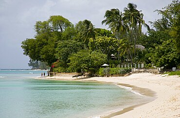 WEST INDIES Barbados St Peter People walking along beach at Gibbes Bay past one of the exclusive houses