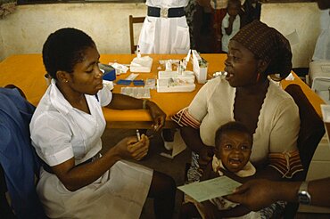 NIGERIA Imo State Medical UNICEF vaccination project.  Female nurse with woman and crying child. Innoculation  injection African Children Female Women Girl Lady Kids Nigerian Western Africa Female Woman Girl Lady