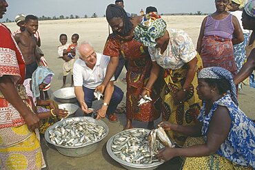 GHANA  People Western man talking to women selling fish on beach near Accra.