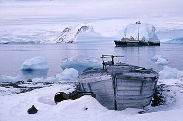 ANTARCTICA  King George Island Old whale boat on land with Greenpeace ship in distance.