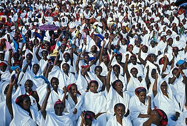 SOMALIA  Politics Independence Day Parade. A mass of seated women with their arms raised in the air dressed in white with colourful headscarfes. Colorful African Eastern Africa Somalian Soomaliya Female Woman Girl Lady Female Women Girl Lady