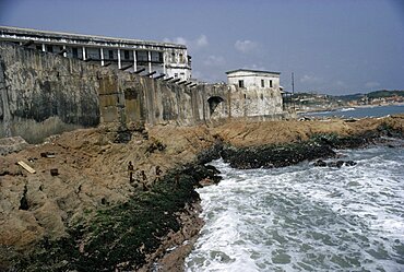 GHANA  Cape Coast Cape Coast Castle.  Line of cannons along seventeenth century castle ramparts with children playing on rocks below. West Africa