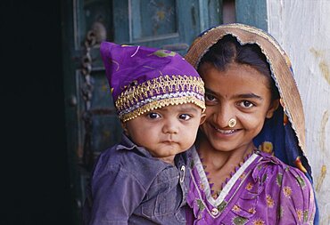 INDIA Gujarat Kutch Dhordo Village.  Girl with nose ring holding young child.