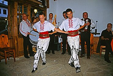 BULGARIA  Arbanassi Male dancers in national costume dancing. Travel Tourism Holiday Vacation Explore Recreation Leisure Sightseeing Tourist Attraction Tour Arbanassi Bulgaria Bulgarian East Eastern Europe European Entertain Entertainer Entertainment Entertaining Folklore Smiling Smile Happy Happiness National Costume Calendar Festival Festive Tradition Traditional Culture Cultural Ethnic Folk Group Man Men Male Gentleman Vivid Vibrant Country Dress Community Village Local Floor Show Dance Dancing Dancer Dancers Restaurant Embroidery Embroidered Sewing Sewn Sew Clothes Clothing Garments Garment Adorn Adornment Smart Fashion Fashionable Wear Wearing Worn Detail Detailed Extrovert Activity Active Pattern Patterned Drum Drummer Music Musical Musician Band Contented Eastern Europe