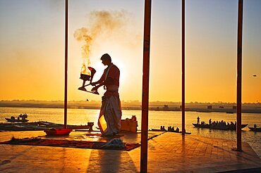 INDIA Uttar Pradesh Varanasi Performing the Ganga Aarti Ceremony at dawn over the River Ganges. India Varanasi Uttar Pradesh Aarti Ceremony River Ganges Faith Hindu Hinduism Tradition Dawn Perform Holy Sacred Sunrise Travel Tourism Holidays Asia Sub-Continent Act Asian Bharat Inde Indian Intiya Performance Public Presentation Religion Religious Hinduism Hindus One individual Solo Lone Solitary