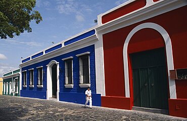 VENEZUELA  Bolivar State Ciudad Red  blue and white painted house frontages near Plaza Bolivar with a person walking past