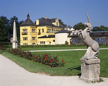 Hellbrunn Palace yellow building seen from across gardens with a unicorn statue in the foreground, Salzburg, Salzburg Province, Austria