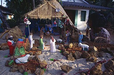 Young girl looking at Christmas nativity scene on sand, Palolem, Goa, India