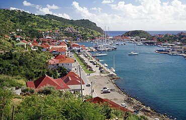 View over the port with yachts on water and houses built along bottom of hillside, Gustavia, St Barthelemy