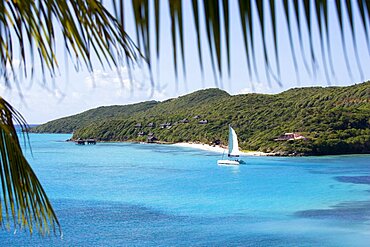 Raffles Resort Hotel with a catamaran leaving Carenage Bay passing the pink Villa Juliet and the Amrita Spa on Godahl Beach, Canouan, St Vincent & The Grenadines