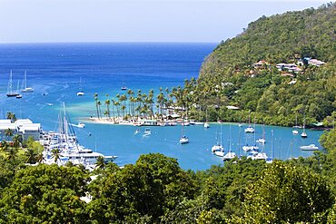 Marigot Bay The harbour with yachts at anchor the and lush surrounding valley, The small coconut palm tree lined beach of the Marigot Beach Club sits at the entrance to the harbour, Castries, St Lucia