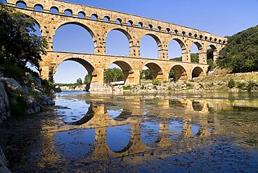 Pont du Gard, UNESCO World Heritage Site, view from west side of the Roman aqueduct in glowing evening light with reflection in the water below, Languedoc-Roussillon, France, Europe