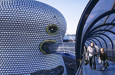 Exterior of the spun aluminium discs of the Selfridges Store and shoppers walking through The Parametric Bridge, a covered footbridge suspended over the street, Bullring Shopping Centre, Birmingham, England, United Kingdom, Europe