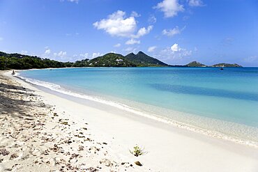 Single person at the waters edge of the calm clear blue water breaking on Paradise Beach in LEsterre Bay with Point Cistern and The Sister Rocks in the distance, Grenada, West Indies, Caribbean, Central America