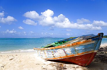 Waves breaking on Paradise Beach at LEsterre Bay with an old fishing boat on the shore and the turqoise sea and Sandy Island sand bar beyond, Grenada