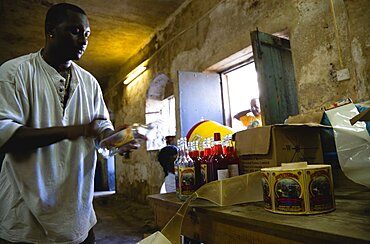 Male worker hand labelling the bottles at the River Antoine rum distillery, Caribbean